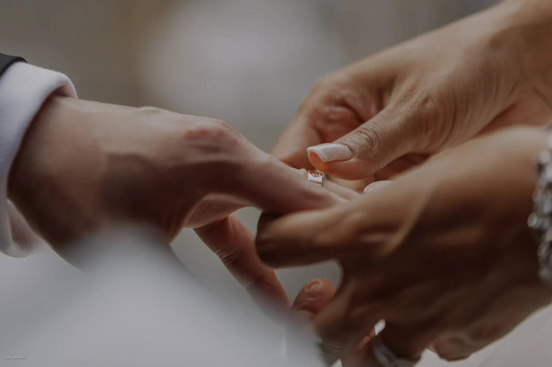 Close view of hands as a ring is slipped onto a finger