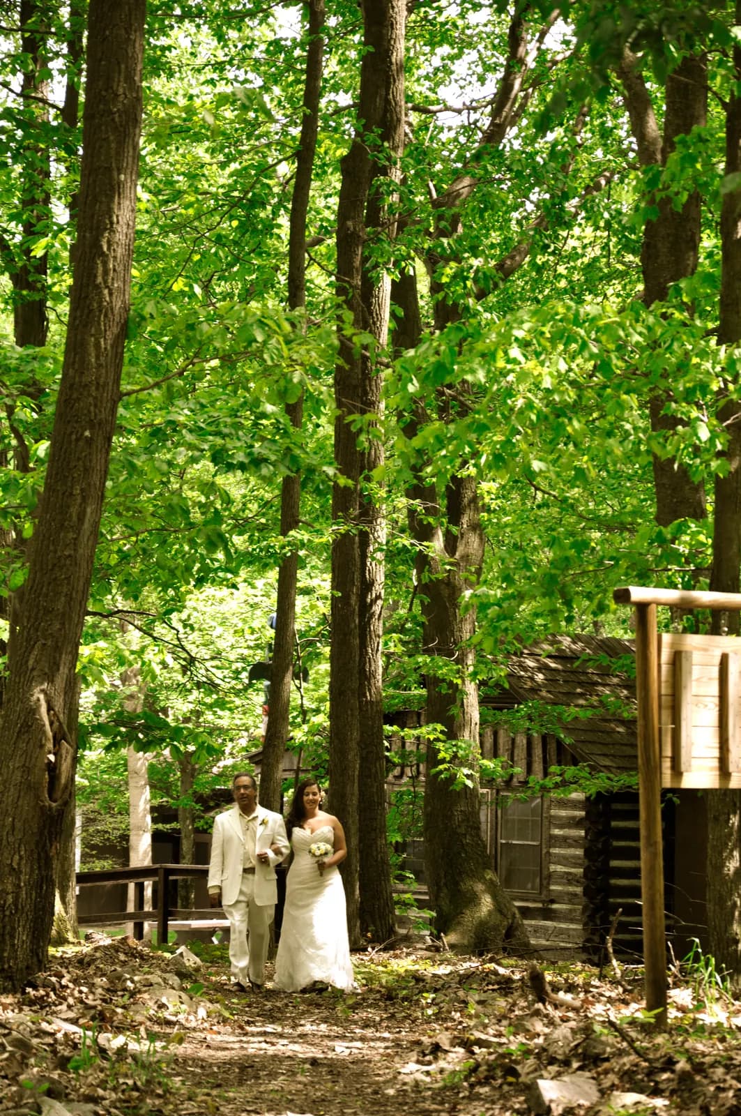 Guests standing at an outdoor woodland chapel under tall green trees