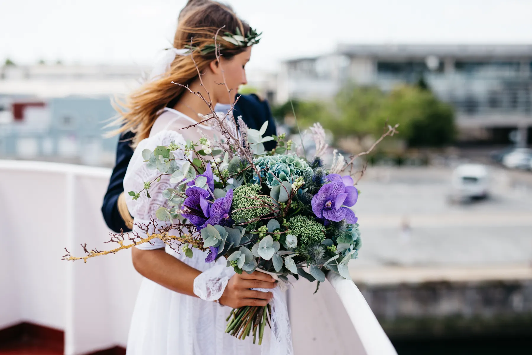 Bride holding a loose wildflower and eucalyptus bouquet by the water